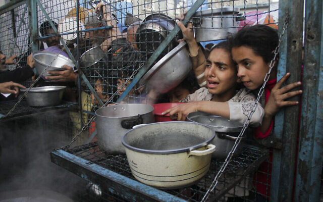 Des enfants palestiniens font la queue pour recevoir des repas gratuits au camp de réfugiés de Jabaliya, dans la bande de Gaza, le 18 mars 2024. (Crédit : AP Photo/Mahmoud Essa)