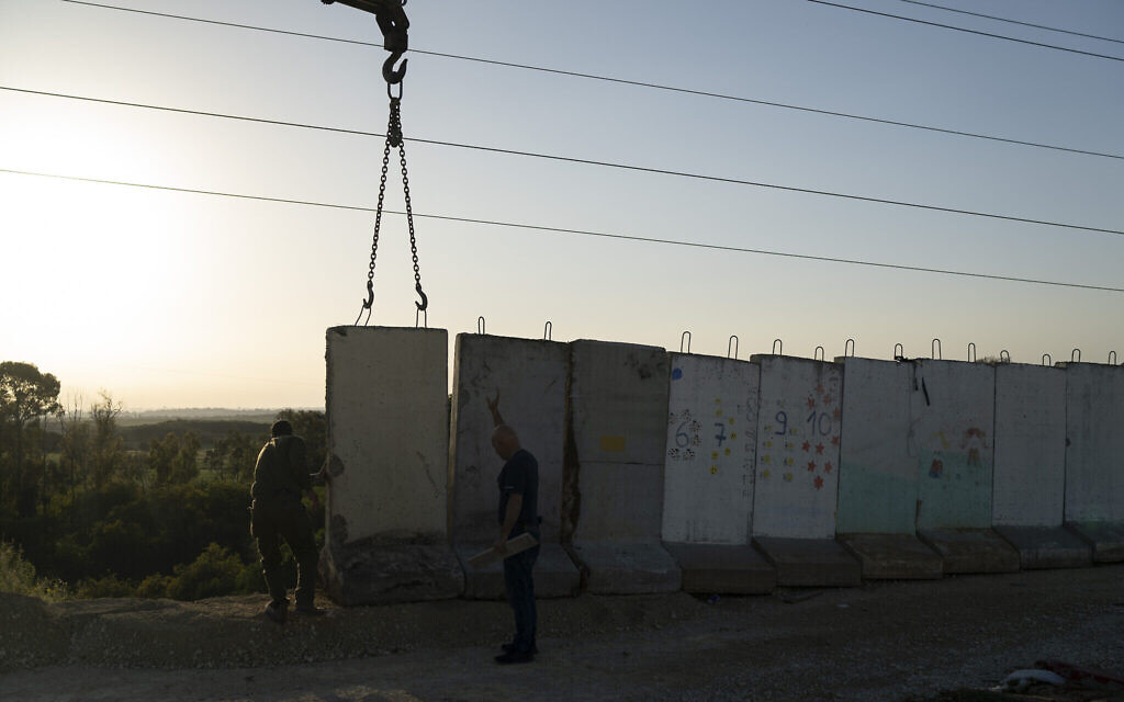 Des ouvriers installent un mur de béton dans une zone située devant un jardin d'enfants, à proximité de la frontière entre Israël et Gaza, à Sderot, en Israël, le 20 mars 2024. (Crédit : AP Photo/Leo Correa)