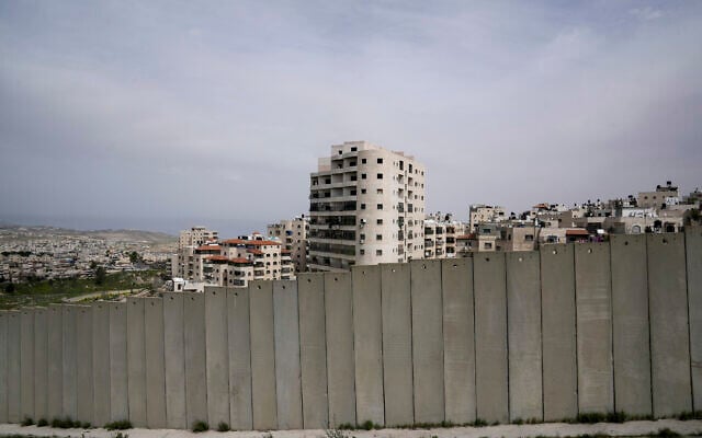 Une vue du camp de réfugiés de Shuafat derrière une partie de la barrière de séparation de la Cisjordanie, à Jérusalem, le 17 mars 2024. (Crédit : Mahmoud Illean/AP) Une vue du camp de réfugiés de Shuafat derrière une partie de la barrière de séparation de la Cisjordanie, à Jérusalem, le 17 mars 2024. (Crédit : Mahmoud Illean/AP)