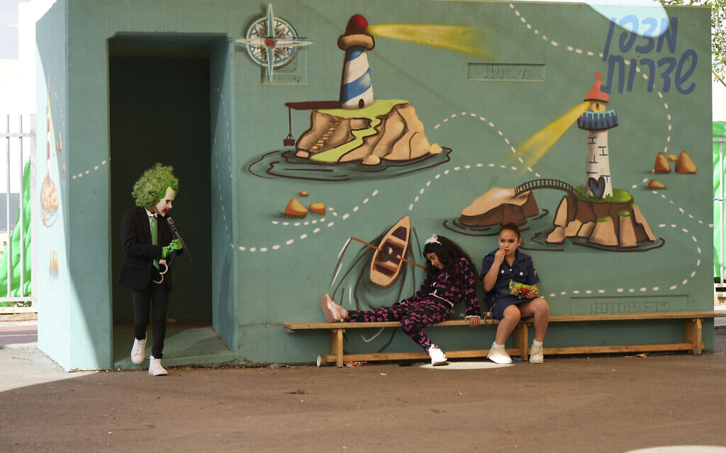 Des enfants israéliens jouent à l'extérieur d'un abri anti-bombes alors qu'ils célèbrent la fête juive de Pourim, à Sderot, dans le sud d'Israël, plus de cinq mois après le massacre du 7 octobre, le vendredi 22 mars 2024. (Crédit : AP Photo/Tsafrir Abayov)