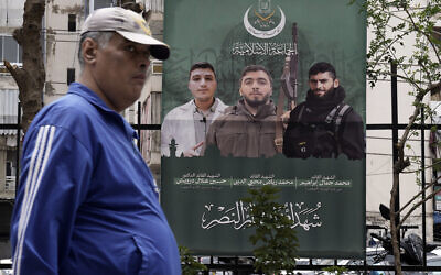 Un homme passe devant une affiche montrant les membres du groupe terroriste Jamaa al-Islamiya qui ont été tués lors d'une frappe israélienne à Beyrouth, au Liban, le 26 mars 2024. (Crédit :AP/Bilal Hussein)