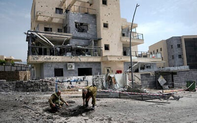 Les forces de sécurité israéliennes examinent un site touché par une roquette tirée depuis le Liban, à Kiryat Shmona, dans le nord d'Israël, le 27 mars 2024. (Crédit : AP Photo/Ariel Schalit)