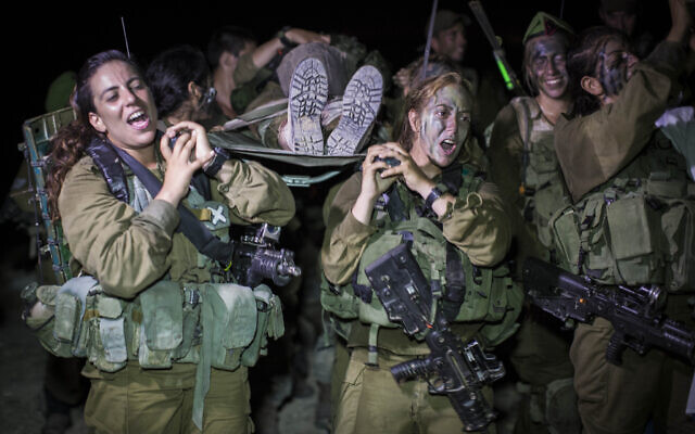 Des soldates du bataillon mixte Caracal de l’armée israélienne transportant une camarade sur une civière à la fin d'un parcours de 16 km pour terminer leur formation, à Tel Nitzan, près de la frontière avec l'Égypte, le 3 septembre 2014. (Crédit : Hadas Parush/Flash90) Des soldates du bataillon mixte Caracal de l’armée israélienne transportant une camarade sur une civière à la fin d'un parcours de 16 km pour terminer leur formation, à Tel Nitzan, près de la frontière avec l'Égypte, le 3 septembre 2014. (Crédit : Hadas Parush/Flash90)