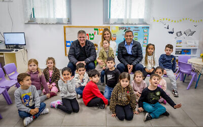 Des responsables - avec le ministre de l'Éducation Yoav Kisch (assis, à gauche) et le maire de Sderot Alon Davidi (assis, à droite) rendent visite à des enfants dans leur classe au premier jour d'école depuis le massacre commis par le Hamas dans le sud d'Israël, le 7 octobre, à Sderot, dans le sud du pays, le 3 mars 2024. (Crédit : Liron Moldovan/Flash90)