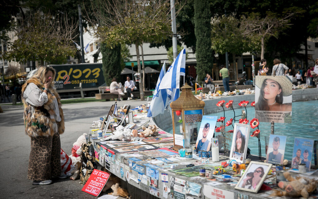 Des habitants de Tel Aviv passent devant des bougies et des photos des victimes du massacre du 7 octobre et des personnes prises en otage par le Hamas à Gaza, le 21 mars 2024. (Crédit : Miriam Alster/Flash90)