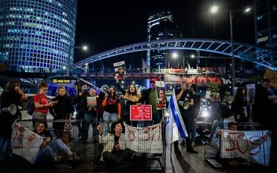 Des manifestants sont assis dans des cages pour évoquer la captivité des otages israéliens de Gaza, à Tel Aviv, le 26 mars 2024. (Crédit : Chaim Goldberg/Flash90)