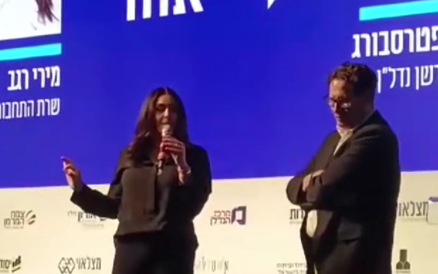 La ministre des Transports tentant de s'exprimer lors d'une conférence à Eilat, avant d'être chassée de la scène, le 27 mars 2024. (Crédit : Treizième chaîne ; utilisée conformément à la clause 27a de la loi sur les droits d'auteur) La ministre des Transports tentant de s'exprimer lors d'une conférence à Eilat, avant d'être chassée de la scène, le 27 mars 2024. (Crédit : Treizième chaîne ; utilisée conformément à la clause 27a de la loi sur les droits d'auteur)