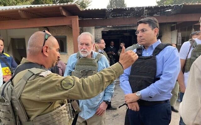 L'ex-gouverneur de l'Arkansas Mike Huckabee (au centre) et le député du Likud Danny Danon (à droite) dans les ruines du kibboutz Kfar Aza, près de la frontière de Gaza, le 20 décembre 2023. (Crédit : Sam Sokol/Times of Israël)
