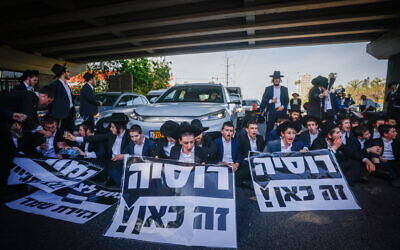Des Juifs ultra-orthodoxes bloquent une route et se heurtent à la police lors d'une manifestation contre la conscription des Haredim dans l'armée israélienne, sur la route 4, à l'extérieur de la ville de Bnei Brak, le 1er avril 2024. (Crédit : Chaim Goldberg/Flash90)