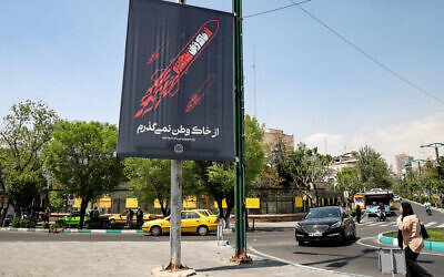Une bannière représentant un missile volant avec un texte en persan disant "Je n'abandonnerai pas ma patrie" est affichée le long d'une rue dans le centre de Téhéran le 15 avril 2024. (Crédit : ATTA KENARE/AFP)