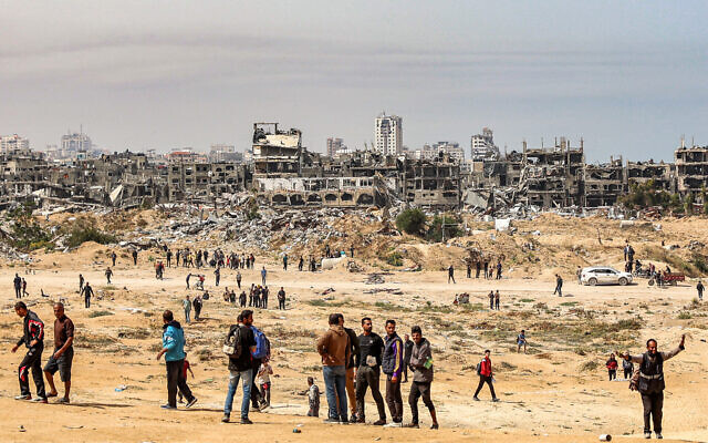 Des personnes attendent l'approche d'un avion qui s'apprête à larguer des colis d'aide humanitaire au-dessus du nord de la bande de Gaza, le 23 avril 2024. (Crédit : AFP) Des personnes attendent l'approche d'un avion qui s'apprête à larguer des colis d'aide humanitaire au-dessus du nord de la bande de Gaza, le 23 avril 2024. (Crédit : AFP)