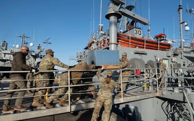 Des soldats de l'armée américaine chargent une unité de climatisation à bord de l'USAV Monterey sur la jetée de la base conjointe Langley-Eustis lors d'une présentation aux médias du déploiement de la 7e brigade de transport à Hampton, en Virginie, le 12 mars 2024. (Crédit : Roberto Schmidt / AFP)
