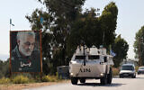 Un véhicule blindé de transport de troupes appartenant à la FINUL passe devant une affiche du commandant iranien Qassem Soleimani, alors qu'il patrouille dans la région de Marjayoun, dans le sud du Liban, le 26 octobre 2023. (Crédit : Anwar Amro/AFP)