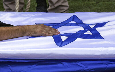 Illustration : Le père du soldat franco-israélien Valentin Elie Ghnassia, tué au combat au kibboutz Beeri lors de l'assaut des terroristes du Hamas, touchant son cercueil lors de ses funérailles, au cimetière du mont Herzl, à Jérusalem, le 12 octobre 2023. (Crédit : Ronaldo Schemidt/AFP)