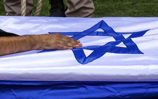 Illustration : Le père du soldat franco-israélien Valentin Elie Ghnassia, tué au combat au kibboutz Beeri lors de l'assaut des terroristes du Hamas, touchant son cercueil lors de ses funérailles, au cimetière du mont Herzl, à Jérusalem, le 12 octobre 2023. (Crédit : Ronaldo Schemidt/AFP)