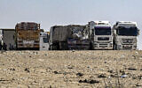 Des camions égyptiens transportant de l'aide humanitaire à destination de la bande de Gaza, en attente à proximité du poste-frontière de Rafah, côté égyptien, le 23 mars 2024. (Crédit : Khaled Desouki/AFP)