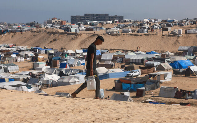 Un Palestinien transportant de l'eau dans un camp de fortune pour les déplacés à Rafah, dans le sud de Gaza, le 4 avril 2024. (Crédit : Mohammed Abed/AFP) Un Palestinien transportant de l'eau dans un camp de fortune pour les déplacés à Rafah, dans le sud de Gaza, le 4 avril 2024. (Crédit : Mohammed Abed/AFP)