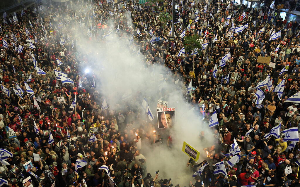 Des parents et des sympathisants des otages israéliens détenus à Gaza depuis l'attaque terroriste du Hamas du 7 octobre tenant des pancartes et agitant des drapeaux israéliens lors d'une manifestation devant le ministère de la Défense, à Tel Aviv, le 6 avril 2024. (Crédit : Jack Guez/AFP)