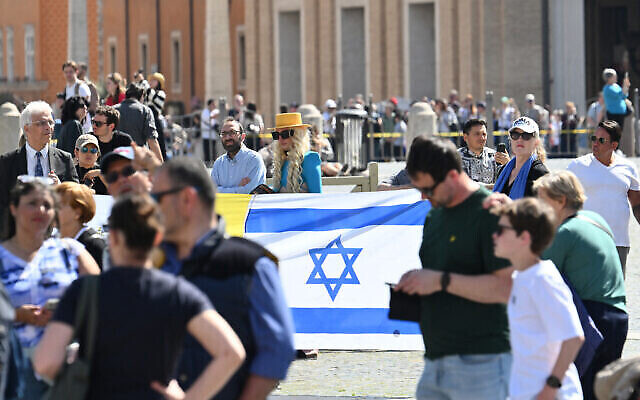Des personnes tiennent un drapeau israélien sur la place Saint-Pierre avant la prière du pape François Regina Coeli le 7 avril 2024 au Vatican. (Alberto Pizzoli/AFP)
