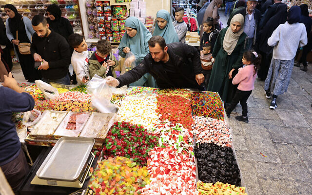Des Palestiniens achetant des bonbons avant l'Aïd al-Fitr, qui marque la fin du Ramadan, dans la Vieille Ville de Jérusalem, le 8 avril 2024. (Crédit : Ahmad Gharabli/AFP)