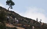 Illustration : Des résidents d’implantations israéliens armés rassemblés sur une colline surplombant le village d'al-Mughayyir, non loin de de Ramallah, en Cisjordanie, le 13 avril 2024. (Crédit : Jaafar Ashtiyeh/AFP)