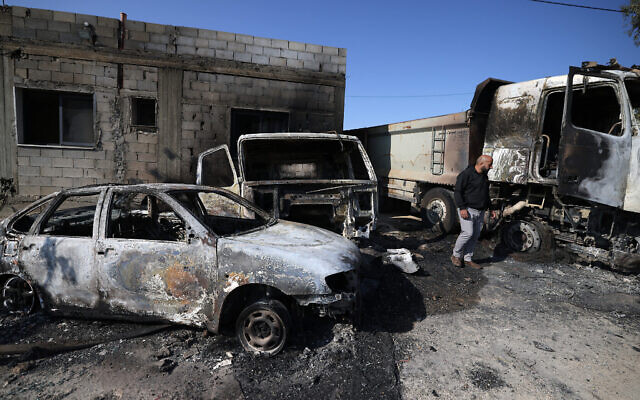 Un Palestinien inspectant les dégâts causés aux véhicules brûlés par des résidents d’implantations israéliens lors d'une attaque sur le village de Mughayir, à proximité de Ramallah, en Cisjordanie, le 13 avril 2024. (Crédit : Jaafar Ashtiyeh/AFP)