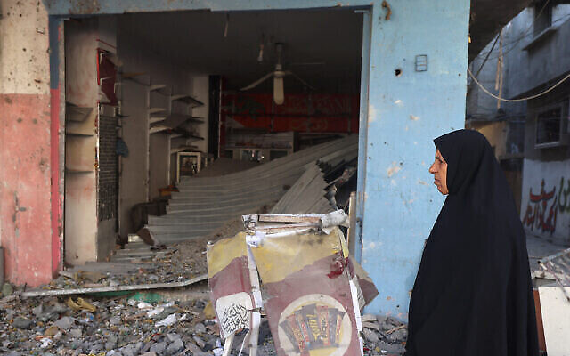 Une Palestinienne passe devant un bâtiment lourdement endommagé par une frappe israélienne la nuit précédente à Rafah, dans le sud de la bande de Gaza, le 17 avril 2024 (Crédit : MOHAMMED ABED / AFP)
