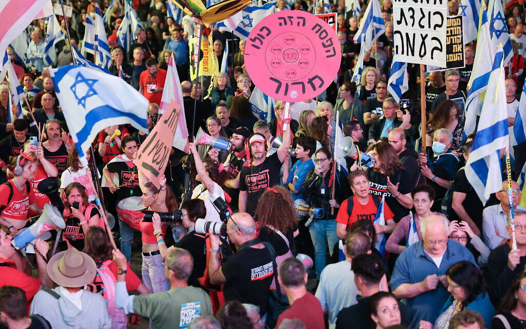 Des Israéliens brandissant des drapeaux nationaux et des pancartes lors d'une manifestation anti-gouvernement, à Tel Aviv, le 20 avril 2024. (Crédit : Jack Guez/AFP)