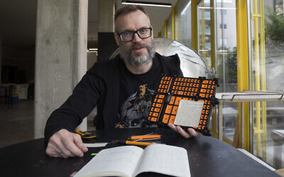 L'artiste autrichien Andreas Joska-Sutanto travaillant sur son projet de transformation du livre "Mein Kampf" d'Adolf Hitler en livre de cuisine, à Vienne, le 25 avril 2024. (Crédit : Alex Halada/AFP)