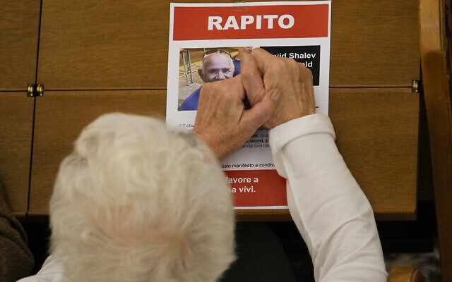 Liliana Segre, survivante de la Shoah et sénatrice, place ses mains sur une affiche à l'effigie d'un Israélien kidnappé lors d'une cérémonie de commémoration organisée par la communauté juive de Milan marquant les 6 mois de l'attaque commise par le Hamas en Israël, le 7 octobre, à Milan, en Italie. Photo prise le 7 avril 2024. (Crédit : AP/Luca Bruno)