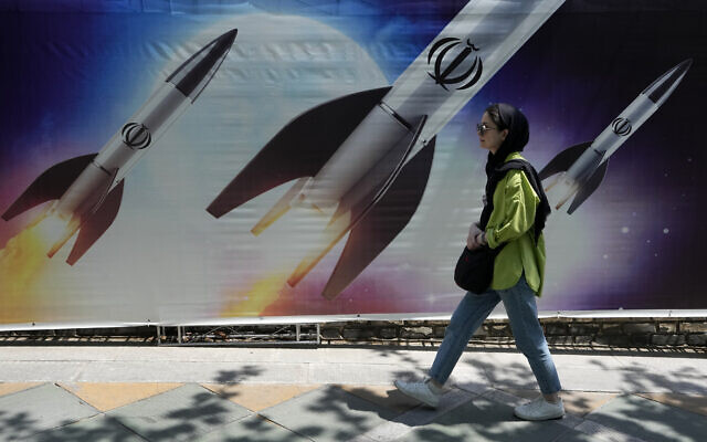Une femme passant devant une bannière montrant des missiles en cours de lancement, dans le nord de Téhéran, en Iran, le 19 avril 2024. (Crédit : Vahid Salemi/AP)