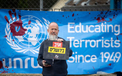Des militants manifestent contre l'Office de secours et de travaux des Nations unies pour les réfugiés de Palestine au Proche-Orient (UNRWA) devant ses bureaux de Jérusalem, le 27 mars 2024. (Crédit : Yonatan Sindel/Flash90)