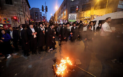 Un drapeau israélien incendié par un adolescent haredi lors d'une manifestation de Frères d'armes, dans le quartier de Mea Shearim, à Jérusalem, le 31 mars 2024. (Crédit : Yonatan Sindel/FLASH90)