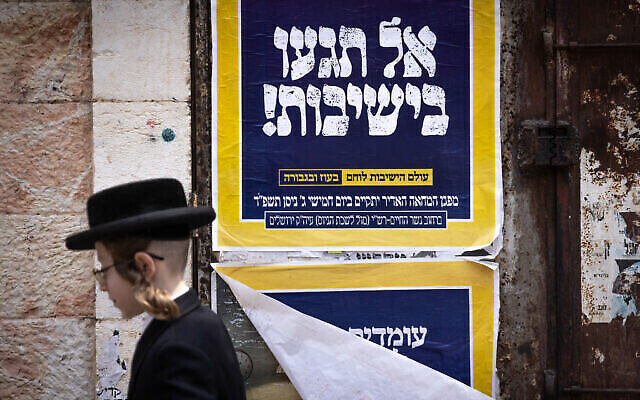 Photo d'illustration : Un Juif ultra-orthodoxe passe devant une affiche contre le service militaire des Haredim. On peut y lire : « Ne touchez pas aux yeshivot », dans le quartier ultra-orthodoxe de Mea Shearim, à Jérusalem, le 9 avril 2024. (Crédit : Chaim Goldberg/Flash90)