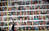 Une personne passant devant des photos de civils israéliens pris en otage par des terroristes du Hamas à Gaza, à Tel Aviv, le 9 avril 2024. (Crédit : Miriam Alster/Flash90)