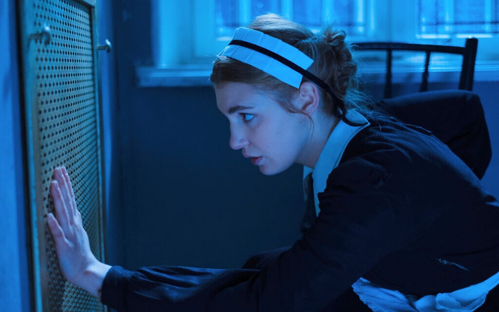 Dans "Irena's Vow", Irena Gut (Sophie Nélisse) accroupie devant la grille qui couvre l'entrée du sous-sol de la maison d'un officier allemand à Tarnopol, en Pologne, où elle cache douze Juifs. (Crédit : Quiver Distribution)