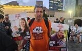 Eli Bibas tenant des photos de ses petits-fils, toujours otages à Gaza, lors d'un rassemblement avant Pessah, à Tel Aviv. (Crédit : Deborah Danan/JTA)