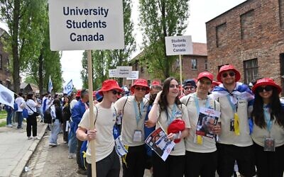 Des étudiants universitaires juifs du Canada brandissent des affiches d'otages de Gaza à l'ancien camp nazi d'Auschwitz, en Pologne, le 6 mai 2024. (Crédit : Canaan Lidor/Times of Israel)