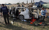 Des membres du personnel des Nations Unies inspectent les restes d'une voiture utilisée par le groupe d'aide américain World Central Kitchen, touchée par une frappe israélienne la veille à Deir al-Balah, dans le centre de la bande de Gaza, le 2 avril 2024. (Crédit : AFP)