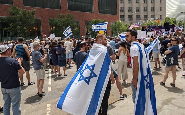 Deux hommes portant des drapeaux israéliens à New York, le 23 mai 2021. (Crédit : Ben Sales/JTA)