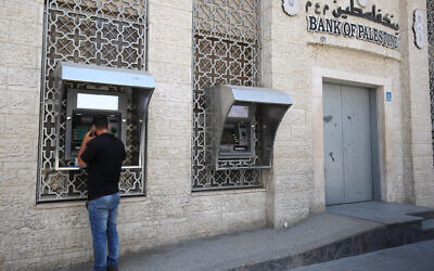 Photo d'illustration : Un Palestinien retire de l'argent à un distributeur de la Banque de Palestine à Khan Younès, dans  le sud de la bande de Gaza, le 15 mai 2018. (Crédit : Said Khatib/AFP)