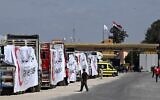 Des camions du Croissant-Rouge égyptien chargés d'aide humanitaire attendent à Rafah, devant le poste-frontière avec la bande de Gaza, le 23 mars 2024, alors que les combats font rage entre Israël et le Hamas. (Crédit : Khaled Desouki/AFP)
