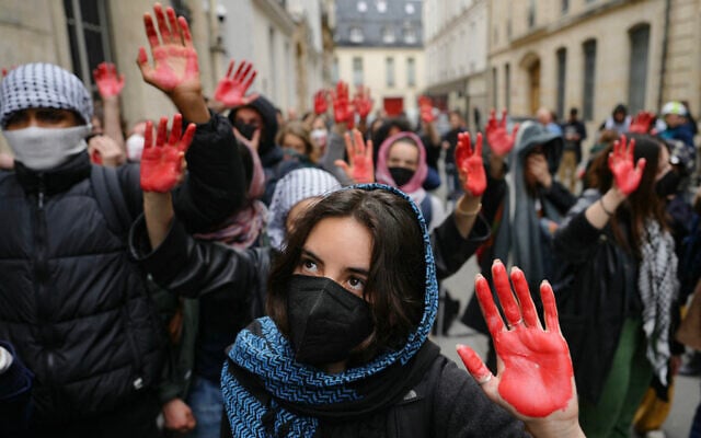 Des manifestants reprenant les "mains ensanglantées" issues du lynchage de soldats israéliens à Ramallah en 2000, alors qu'ils participent à une manifestation anti-Israël, devant l'Institut d'études politiques (Sciences Po Paris) occupé par des étudiants, à Paris, en France, le 26 avril 2024. (Crédit : Dimitar Dilkoff/AFP)