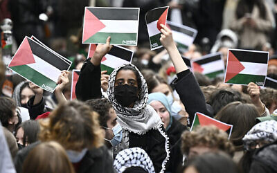 Illustration : Des manifestants brandissant des affiches du drapeau palestinien alors qu'ils manifestent près de l'entrée de l'Institut d'études politiques de Sciences Po Paris, occupé par des étudiants anti-Israël, à Paris, France, le 26 avril 2024. (Crédit : Julien De Rosa/AFP)
