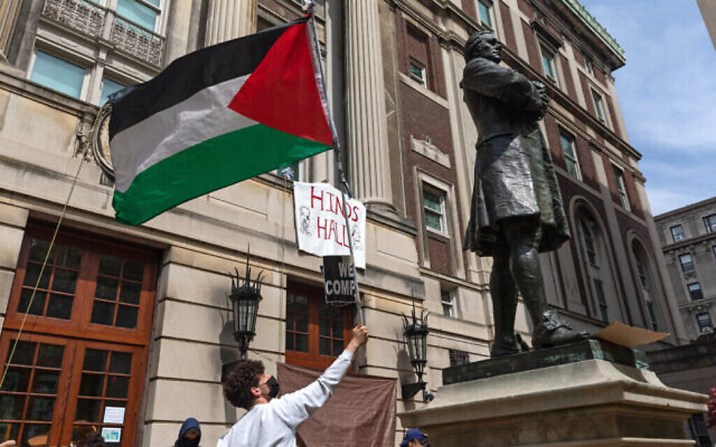 Des étudiants anti-Israël brandissant un drapeau palestinien alors qu’ils se rassemblent sur les marches du Hamilton Hall de l’Université Columbia, à New York, le 30 avril 2024. (Crédit : Emily Byrski/AFP)