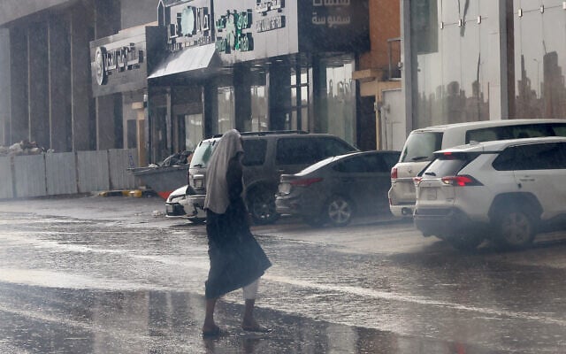 Un homme se couvrant la tête alors qu'il traverse une rue inondée sous la pluie dans la capitale saoudienne Ryad, suite aux vents forts et aux fortes pluies de la nuit qui ont inondé les routes dans différentes régions du royaume désertique, le 1er mai 2024. (Crédit : Fayez Nureldine/AFP)