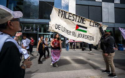 Des étudiants anti-israéliens accrochent une banderole sur laquelle on peut lire "Libérez la Palestine de la mer au Jourdain", lors d'une manifestation à l'université de Lausanne, en Suisse, le 4 mai 2024. (Crédit : Fabrice Coffrini/AFP)