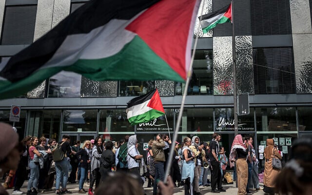 Des étudiants anti-Israël et des activistes brandissant des drapeaux palestiniens lors d'une manifestation à l'entrée du bâtiment Geopolis de l'Université de Lausanne (UNIL), occupé par des étudiants pro-palestiniens, à Lausanne, le 4 mai 2024. (Crédit : Fabrice Coffrini/AFP) Des étudiants anti-Israël et des activistes brandissant des drapeaux palestiniens lors d'une manifestation à l'entrée du bâtiment Geopolis de l'Université de Lausanne (UNIL), occupé par des étudiants pro-palestiniens, à Lausanne, le 4 mai 2024. (Crédit : Fabrice Coffrini/AFP)