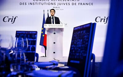 Le Premier ministre français Gabriel Attal (G) prononce un discours devant une table avec des portraits d'otages israéliens détenus à Gaza lors du dîner annuel du Conseil représentatif des institutions juives de France (CRIF) au Carrousel du Louvre à Paris, le 6 mai 2024. (Crédit : JULIEN DE ROSA / AFP)