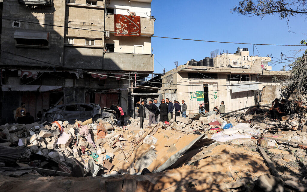 Des personnes inspectant un cratère d'impact sur le site d'un bâtiment touché par des frappes israéliennes à Rafah, dans le sud de la bande de Gaza, le 8 mai 2024. (Crédit : AFP)